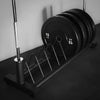 Storage rack for weight plates and barbells on a black floor and grey wall