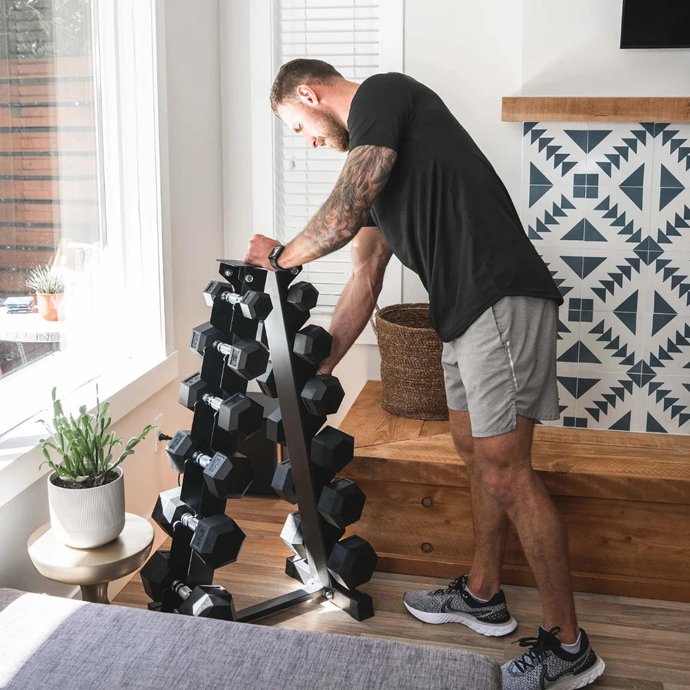 Man organizing a stack of dumbbells in a home setting.