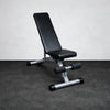 Black weight bench with silver legs on a gray floor against a white wall