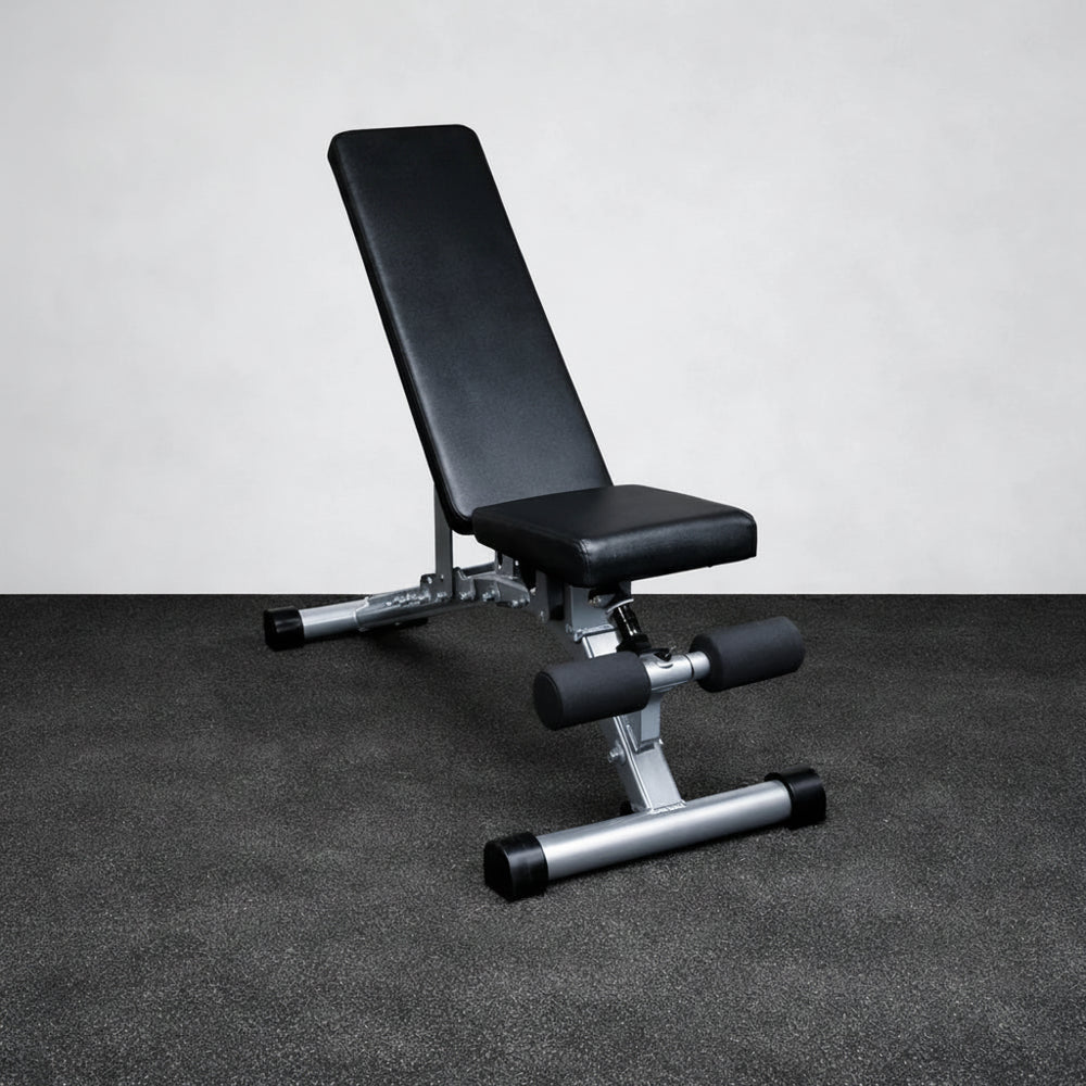 Black weight bench with silver legs on a gray floor against a white wall