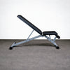 Black adjustable weight bench on a gray floor with a white background