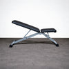 Black adjustable weight bench on a gray floor with a white wall background