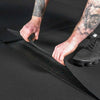 Man lifting thick black gym floor tiles
