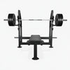 Black gym bench in flat position with barbell and weights above on a white background