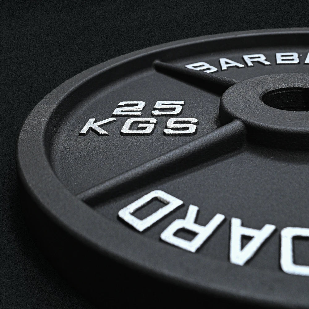 Close up of a 25kg black weight plate on a black background