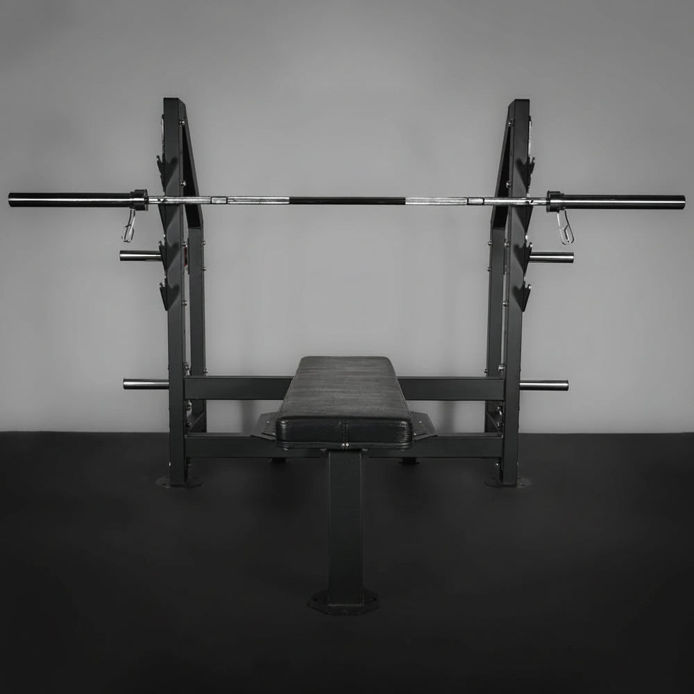 Weight bench with barbell on a dark floor and gray wall