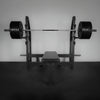 Barbell with weights on a weight rack against a plain wall.