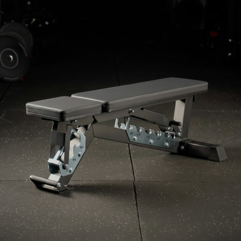 Adjustable weight bench on a dark floor with gym equipment in the background
