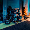 Set of dumbbells and kettlebell on a windowsill with a cityscape view.