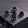 Black gym bar holder with multiple holes on a gray surface