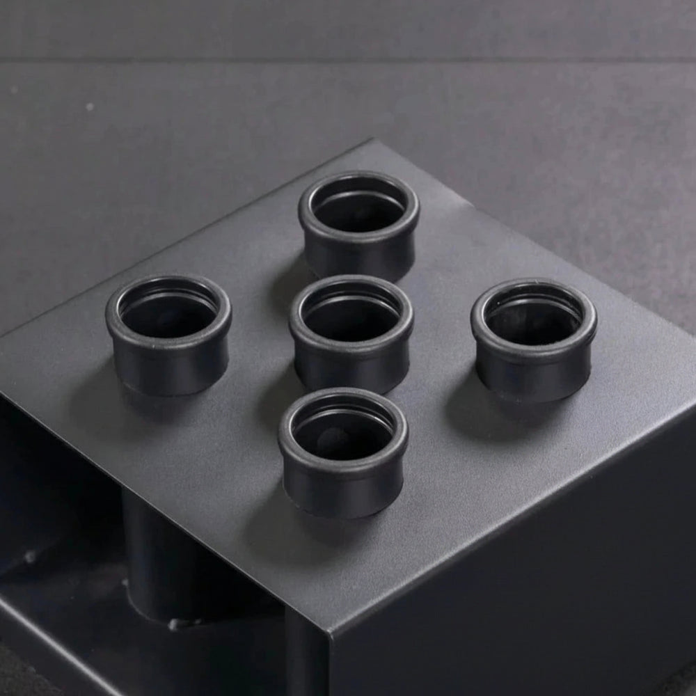 Black gym bar holder with multiple holes on a gray surface