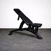 Black adjustable weight bench on a gray floor with a white background