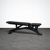 Black adjustable weight bench on a gray floor with a white wall background