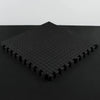 Stack of black interlocking foam mats on a dark background
