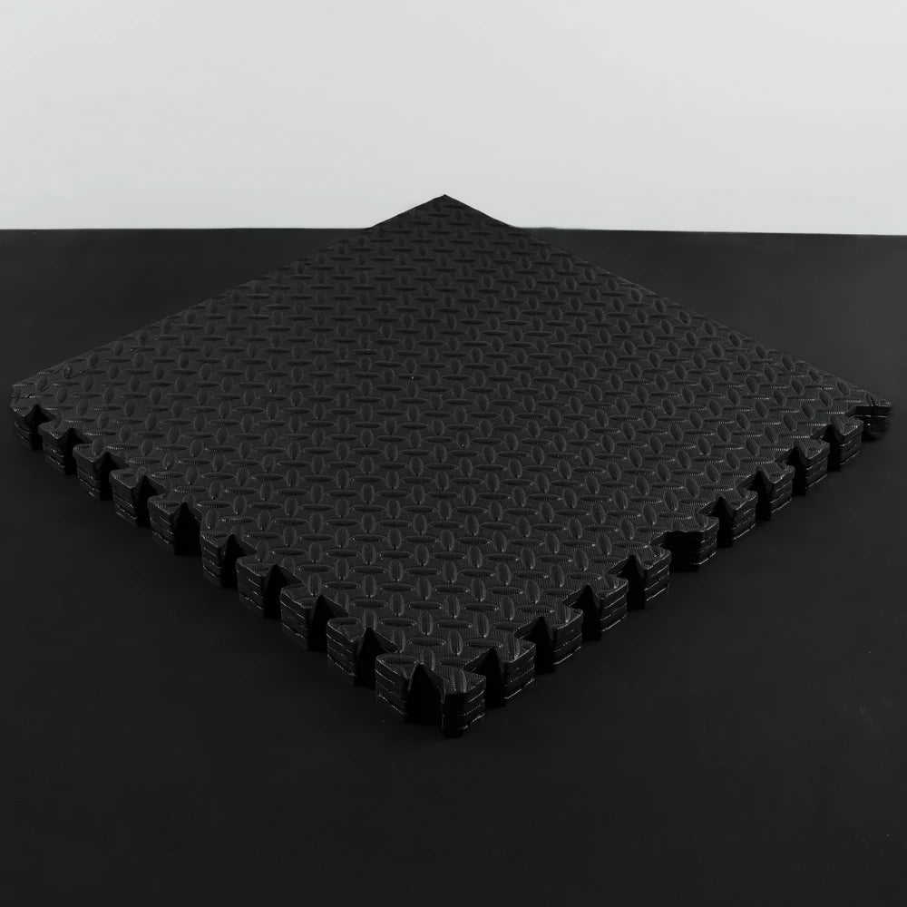 Stack of black interlocking foam mats on a dark background