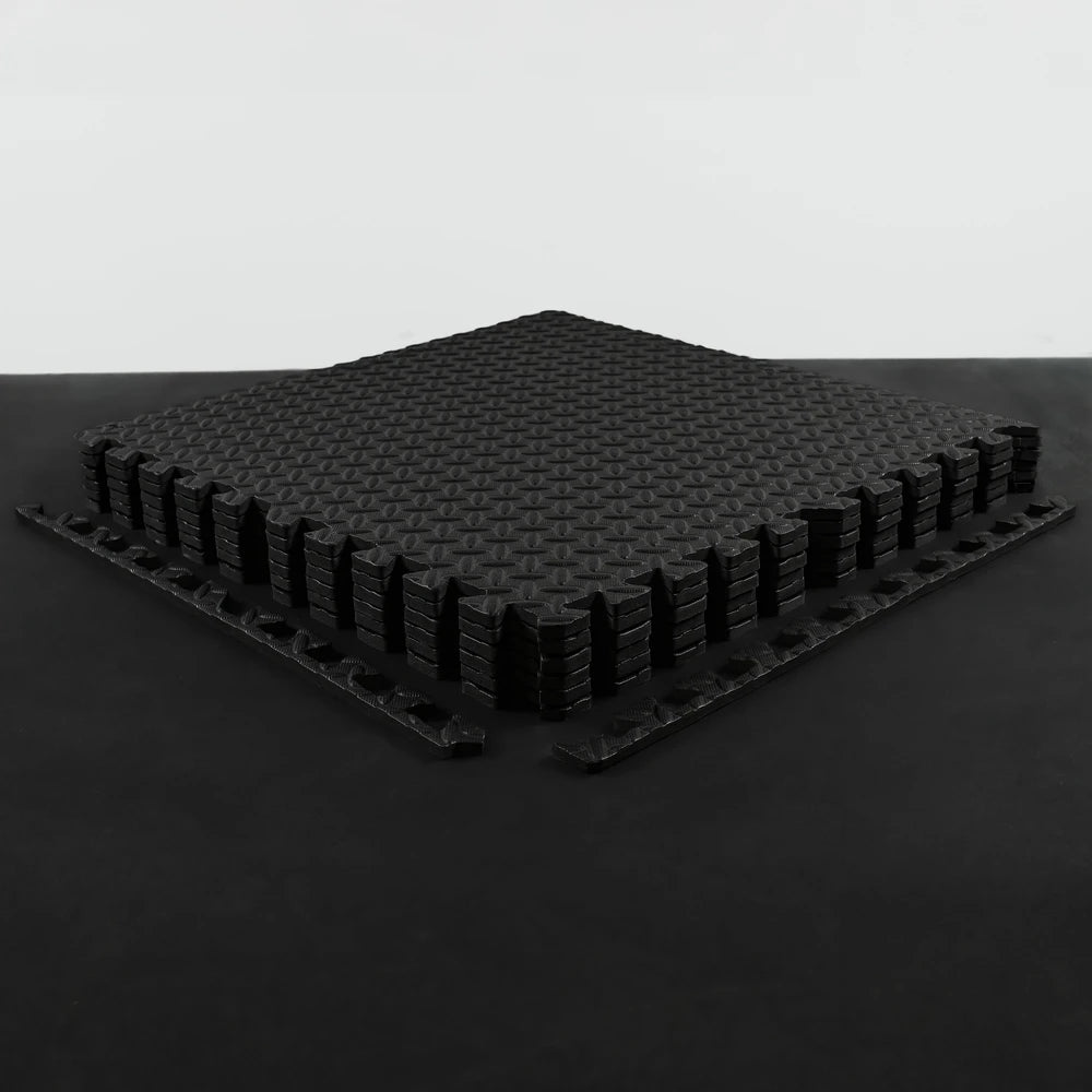 Black interlocking foam mats on a black surface with a light gray background