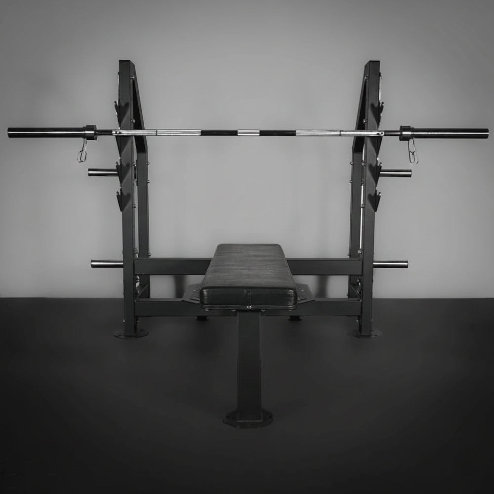 Weight bench with barbell on a dark floor and gray wall background