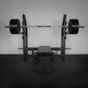 Barbell with weights on a weight rack against a plain wall.