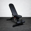 Black adjustable gym bench on a gray floor with a white wall background