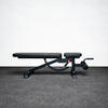Black adjustable weight bench on a gray floor with a white wall background
