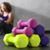Colorful dumbbells with weight markings on a surface, with a blurred person in the background.