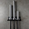 Metal wall-mounted rack with cylindrical hooks on a concrete wall.