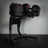 Pair of adjustable dumbbells on a stand against a gray background