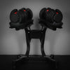 Pair of adjustable dumbbells on a stand against a dark background