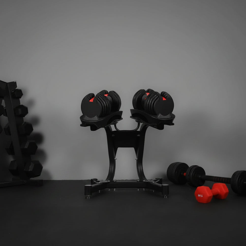 Set of adjustable dumbbells on a stand with additional dumbbells on a gray background