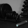 Gym weight plates and barbell on a dark surface with a gray background