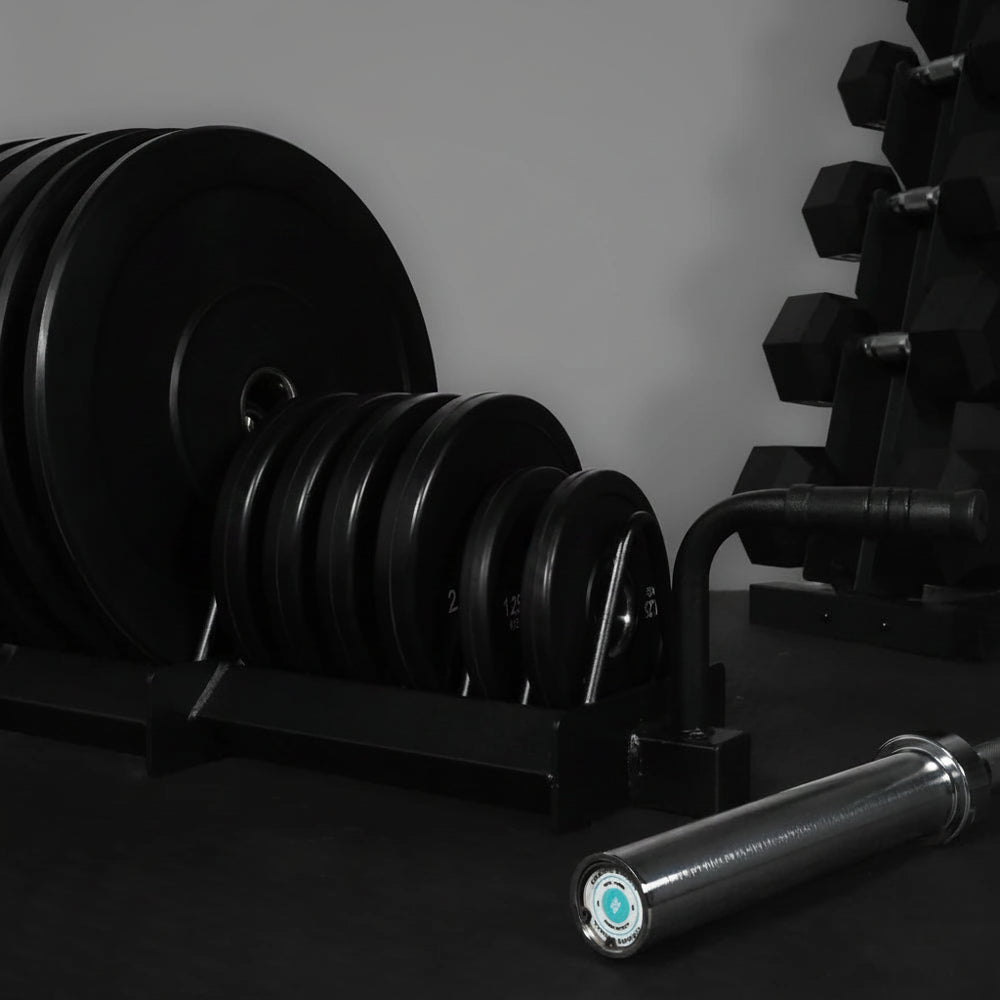 Gym weight plates and barbell on a dark surface with a gray background