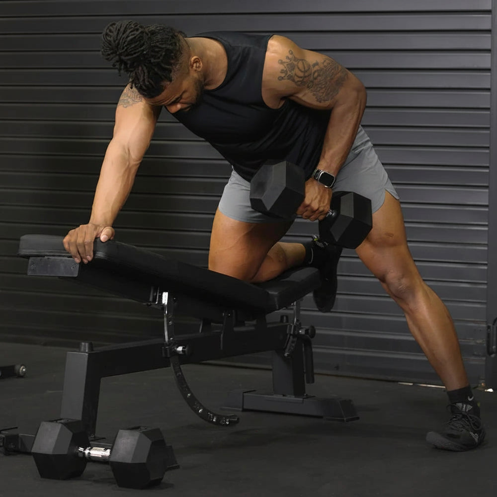 Man exercising with dumbbells on a bench in a gym setting