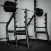 Weightlifting rack with barbell on a plain background