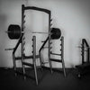 Gym weight rack with barbells against a plain wall
