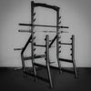 Gym rack with multiple barbells on a dark floor and light gray wall