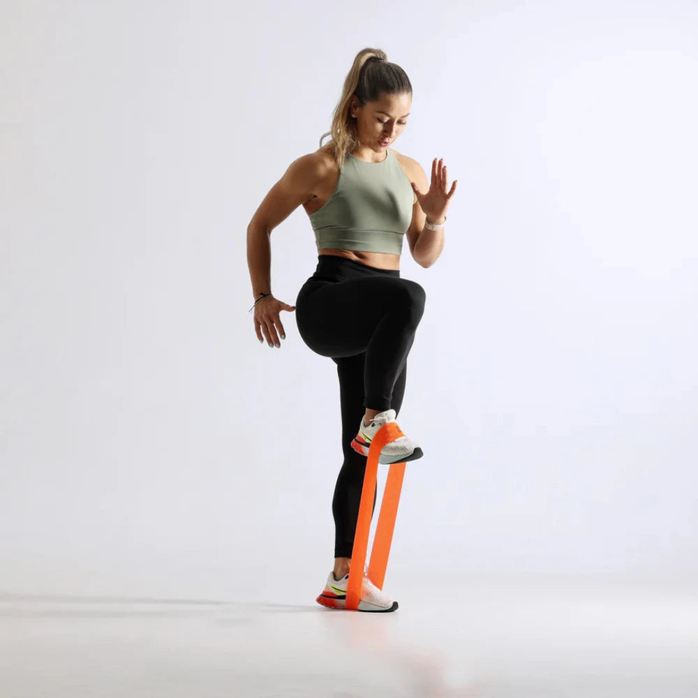 Woman exercising with an orange resistance band on a white background