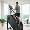 Man using a step machine in a modern indoor setting with large windows.