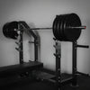 Barbell with weights on a squat rack in a gym setting