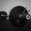 Close-up of a barbell with weight plates on a gray background