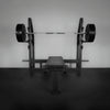 Barbell with weights on a weight rack against a plain wall.