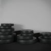 Stacks of black weight plates on a dark surface with a neutral background