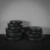Stack of black weight plates on a dark surface with a gray background