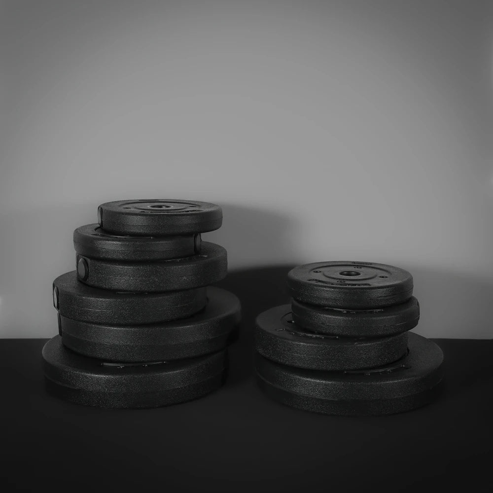 Stack of black weight plates on a dark surface with a gray background