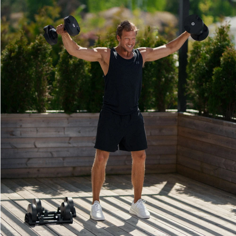 Man exercising with dumbbells outdoors on a wooden deck