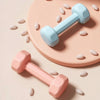 Two colorful dumbbells on a beige surface with scattered pills.