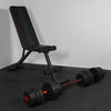Black adjustable weight bench with dumbbells on a gray surface