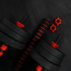 Pair of black dumbbells with red attachments on a dark background