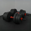 Pair of black adjustable dumbbells with red accents on a dark surface.