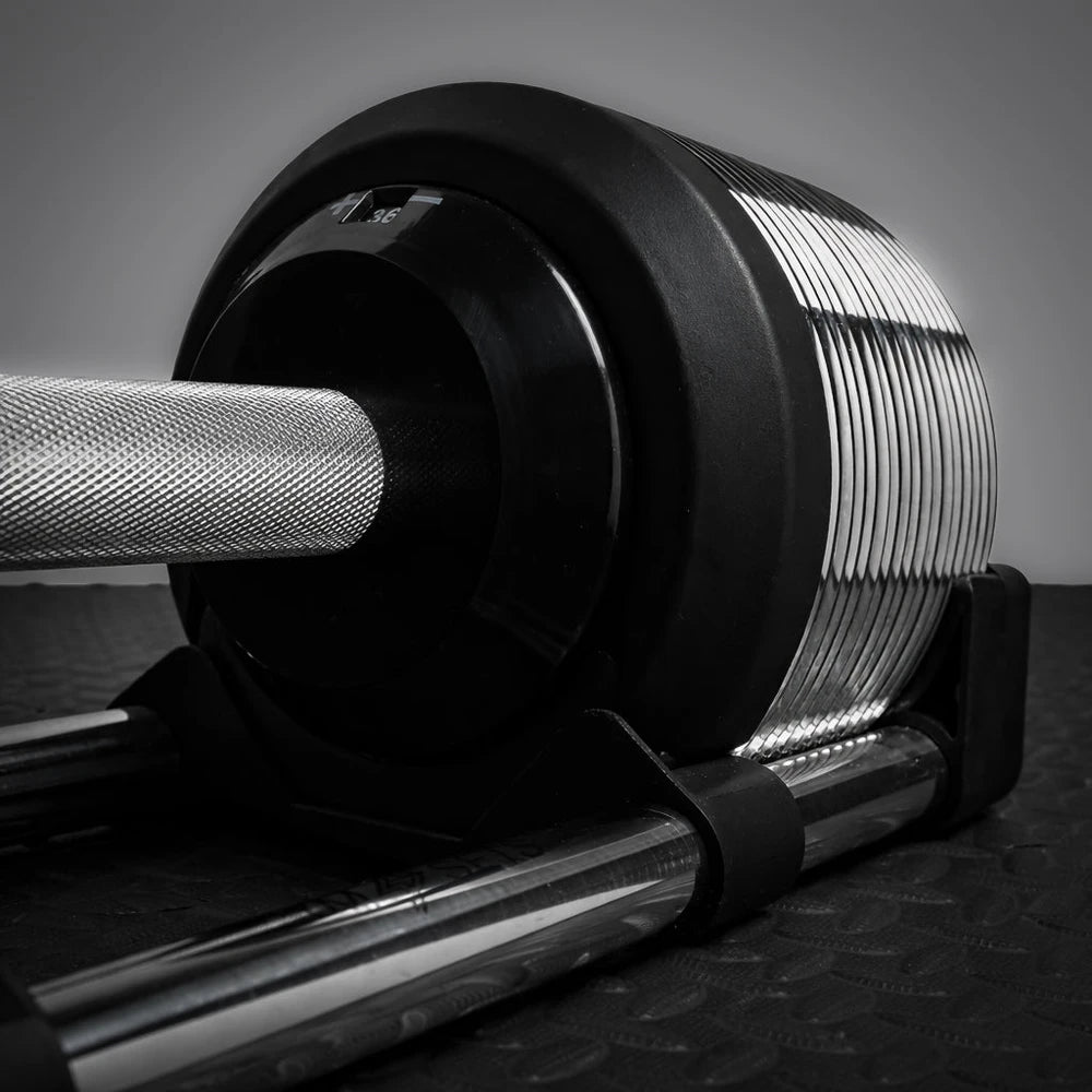 Close-up of a barbell with weight plates on a dark surface