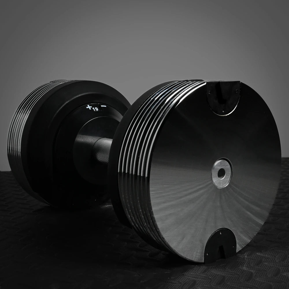 Pair of black dumbbells on a dark surface with a gray background
